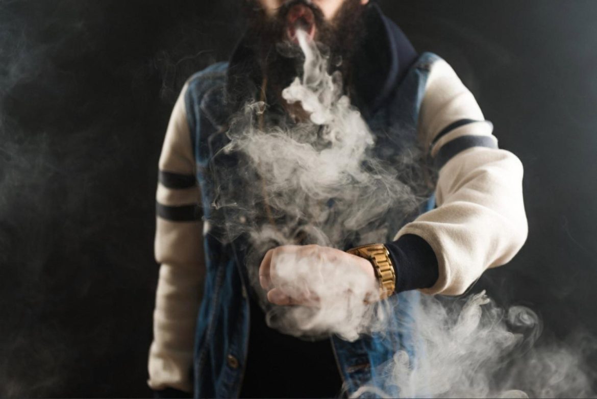 Man in Dubai exhaling vapour from an e-liquid vape device on a dark background